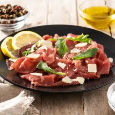Eleganckie carpaccio z wołowiny z rukolą i parmezanem, podane z cytryną, oliwą i pieprzem.