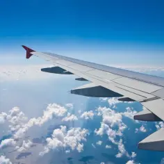 Widok z okna samolotu na chmury i ocean. Zastanawiasz się, ile się leci na Dominikanę z Warszawy?