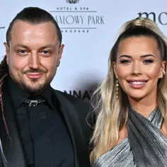 Baron z żoną, uśmiechnięci, pozują do zdjęcia. On ma warkocze, ona błyszczącą sukienkę.