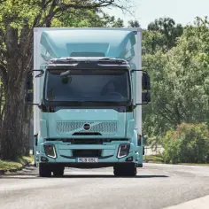 Nowy, elektryczny Volvo FL jedzie drogą wśród zieleni.