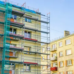 Budynek w remoncie, rusztowania i siatka ochronna. Balkony we wspólnocie mieszkaniowej czekają na odnowienie.