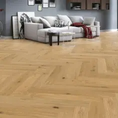 Piękny parkiet na podłogę w salonie, ułożony we wzór jodełki. Jasne drewno dodaje ciepła i elegancji.