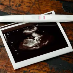 Pozytywny test ciążowy i zdjęcie USG. To już 7 tydzień ciąży, wielkość dziecka jest widoczna na obrazie.