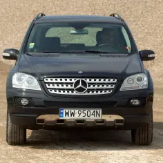 Czarny Mercedes ML 320 z polskimi tablicami rejestracyjnymi WW 9504N stoi na drodze usypanej żwirem.