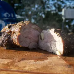Soczysta karkówka na grillu elektrycznym, przyprawiona ziołami, leży na drewnianej desce.