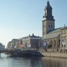 Malowniczy widok na kanał i zabytkowe budynki w jednym z miast Szwecji. W tle dumnie wznosi się wieża kościelna.