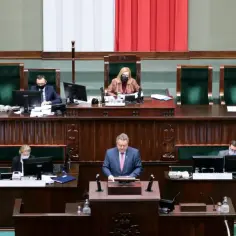 Posłowie w sejmie, dyskusja o tym, ile zarabia poseł. W tle polska flaga.