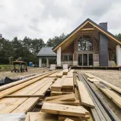 Drewno na budowie domu, gotowe do montażu. Warto pomyśleć o ubezpieczeniu domu w budowie, by chronić inwestycję.