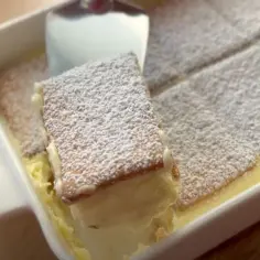 Tanie ciasto bez pieczenia z herbatnikami i kremem, posypane cukrem pudrem. Idealne na szybki deser.