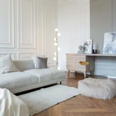 Elegancki salon z sofą, dywanem i sztukaterią na ścianach. Panele ścienne dodają wnętrzu klasycznego charakteru.