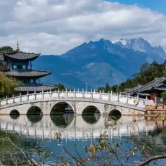 Kamienny most łukowy nad jeziorem, w tle pagody i góry. Chiny ciekawostki, jak z obrazka.