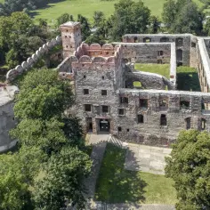 Ruiny zamku w Ząbkowicach Śląskich, z charakterystyczną okrągłą basteją i ceglanymi murami, otoczone zielenią.
