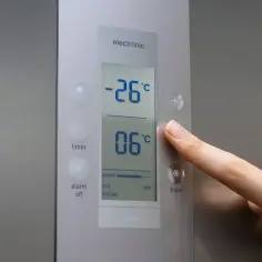 Palec naciska przycisk na panelu lodówki, pokazującym -26°C i 06°C. Sprawdzam, ile stopni w lodówce.