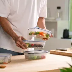 Przygotowanie posiłków do pojemników to pierwszy krok, jak otworzyć catering. Widać tu zdrowe jedzenie i świeże warzywa.