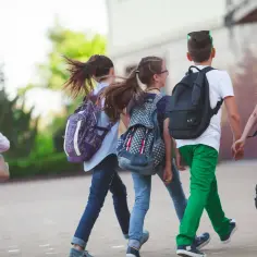 Dzieci z plecakami biegną na wolność, kiedy zawodówka kończy szkołę.