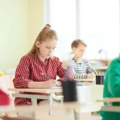 Dzieci piszą testy w szkole. Zastanawiają się, czy ocena z diagnozy wlicza się do średniej.