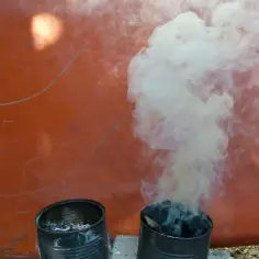 Dwa metalowe pojemniki z żarem, z których unosi się gęsty dym. Zastanawiasz się, dlaczego dym z komina leci w dół? To zjawisko atmosferyczne.