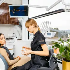 Dentystka wyjaśnia pacjentce, jak radzić sobie z pulsującym bólem zęba, używając modelu szczęki.