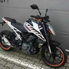 Czarny KTM Duke 390, zarejestrowany na 125, z pomarańczowymi akcentami na felgach i owiewkach, stoi na chodniku.