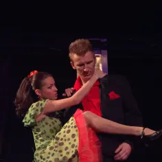 Tancerze w kostiumach z musicalu "Grease" w Warszawie. Ona w zielonej sukience w grochy, on w czarnej marynarce.