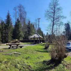 Drewniana altana, ławki i stół piknikowy w otoczeniu lasu i potoku. Idealne miejsce na odpoczynek, odkryj Kocierz atrakcje!