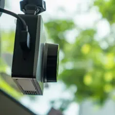 Wideorejestrator zamontowany na szybie, z widocznym kablem zasilającym. Dowiedz się, jak podłączyć wideorejestrator do instalacji samochodowej.