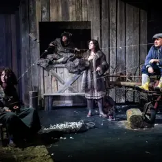 Cztery postacie na scenie, przygotowujące się do teatralnego tournee. Scenografia przypomina wiejską stodołę.