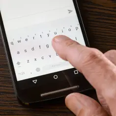Palec naciska klawisz "u" na klawiaturze Samsunga. Dowiedz się, jak włączyć autokorektę Samsung, aby pisać szybciej i bez błędów.