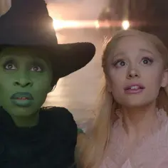 Zielona wiedźma i blondynka o wielkich oczach, dwie **wicked musical characters**, patrzą w górę z zaskoczeniem.