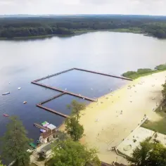 Wakacje nad jeziorem w Antoninie: piaszczysta plaża, drewniane pomosty i kąpielisko.