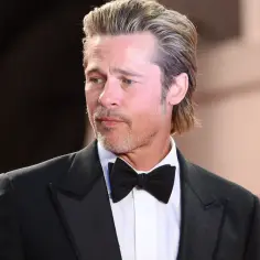 Brad Pitt w eleganckim smokingu z muszką, jego wiek dodaje mu charyzmy.