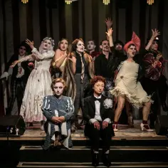 Aktorzy w teatralnych strojach na scenie w Warszawie. Lipiec przyniósł emocje na deskach teatru.