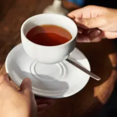 Dwie dłonie trzymają filiżankę z naparem z czystka. Zbyt długie parzenie może powodować gorzki smak.