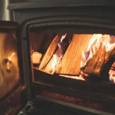 Płonące drewno w otwartym piecyku, widok przez szybę.
