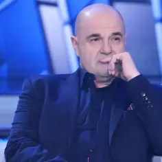 Cezary Żak w eleganckim garniturze, zamyślony, jakby przygotowywał się do roli w teatrze.