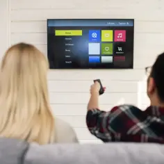 Para relaksuje się przy muzyce. Na ekranie telewizora widać menu aplikacji, w tym "My music", które przypomina interfejs Spotify na telewizorze.