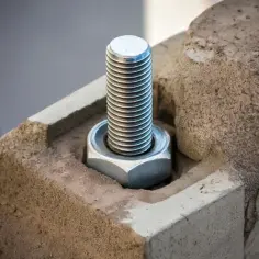 Metalowa śruba z nakrętką, czyli kotwa, mocno osadzona w betonowym elemencie.