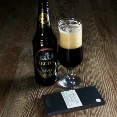 Jak dobrać piwo do deseru z gorzkiej czekolady? Porter Ciechan i tabliczka czekolady "Original Beans" na drewnianym blacie.