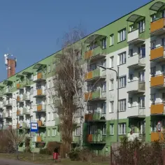 Długi blok mieszkalny z zielono-białą elewacją i balkonami. Zastanawiasz się, czy za mieszkanie spółdzielcze własnościowe płaci się podatek od nieruchomości?