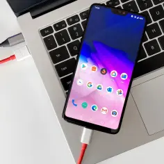 Telefon podłączony do laptopa kablem, gotowy do transferu zdjęć na pendrive.
