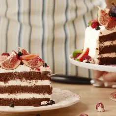 Obłędny tort czekoladowy z mascarpone i owocami: kawa na talerzu, obok cały tort na paterze.