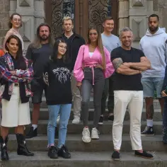 Grupa uczestników programu "The Traitors" pozuje na schodach.