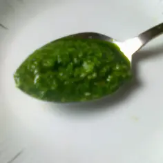 Łyżka pełna aromatycznego pesto z pietruszki, gotowa do podania na białym talerzu.