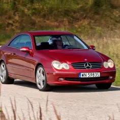Czerwony Mercedes CLK W209 z kierowcą przemierza malowniczą, wiejską drogę.