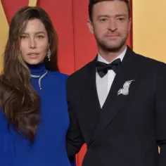 Jessica Biel i Justin Timberlake na czerwonym dywanie. Ona w niebieskiej sukni z biżuterią, on w czarnym smokingu z ozdobną przypinką.