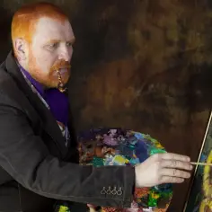 Mężczyzna z rudą brodą i fajką w ustach maluje słoneczniki, przypominając słynne van Gogh obrazy.