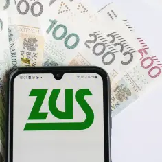 ZUS na ekranie telefonu, obok banknotów 100, 200 i 500 zł. Tabela waloryzacja emerytury może być kluczem do zrozumienia przyszłych świadczeń.