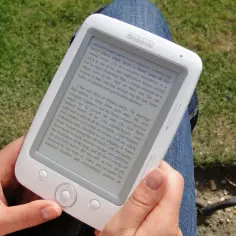 Osoba czyta książkę na czytniku Bookeen. Ta aplikacja do czytania książek pozwala zabrać ze sobą całą bibliotekę.