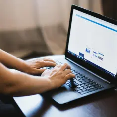 Osoba tworzy zaproszenia w Wordzie, wpisując tekst na laptopie.