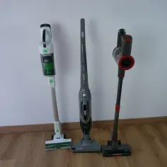 Trzy odkurzacze bezprzewodowe stojące obok siebie na drewnianej podłodze.